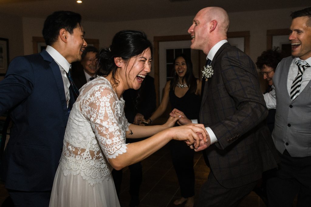 wedding couple laughing with bride sitting on grooms knee at their intimate elopement wedding