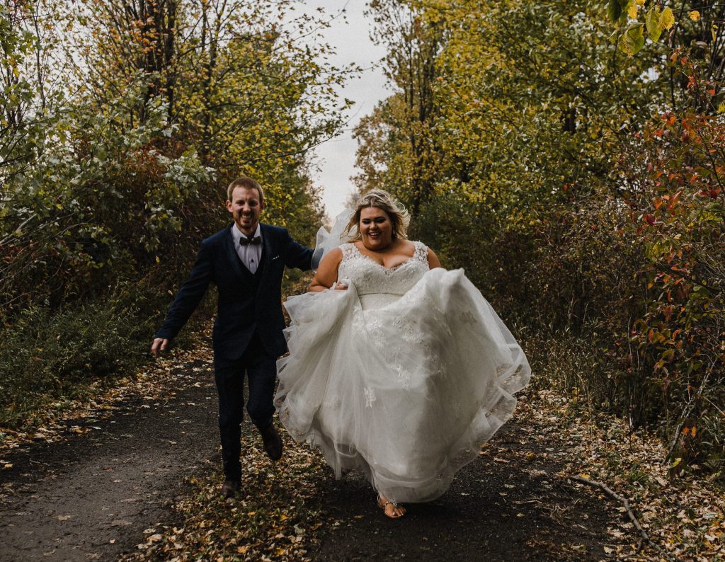 wedding couple running down a laneway in the fall at their intimate home wedding in ottawa