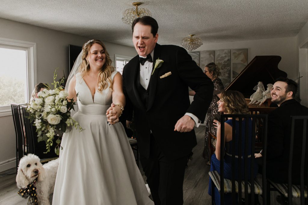 bride and groom dancing down the aisle after getting married at their intimate home wedding