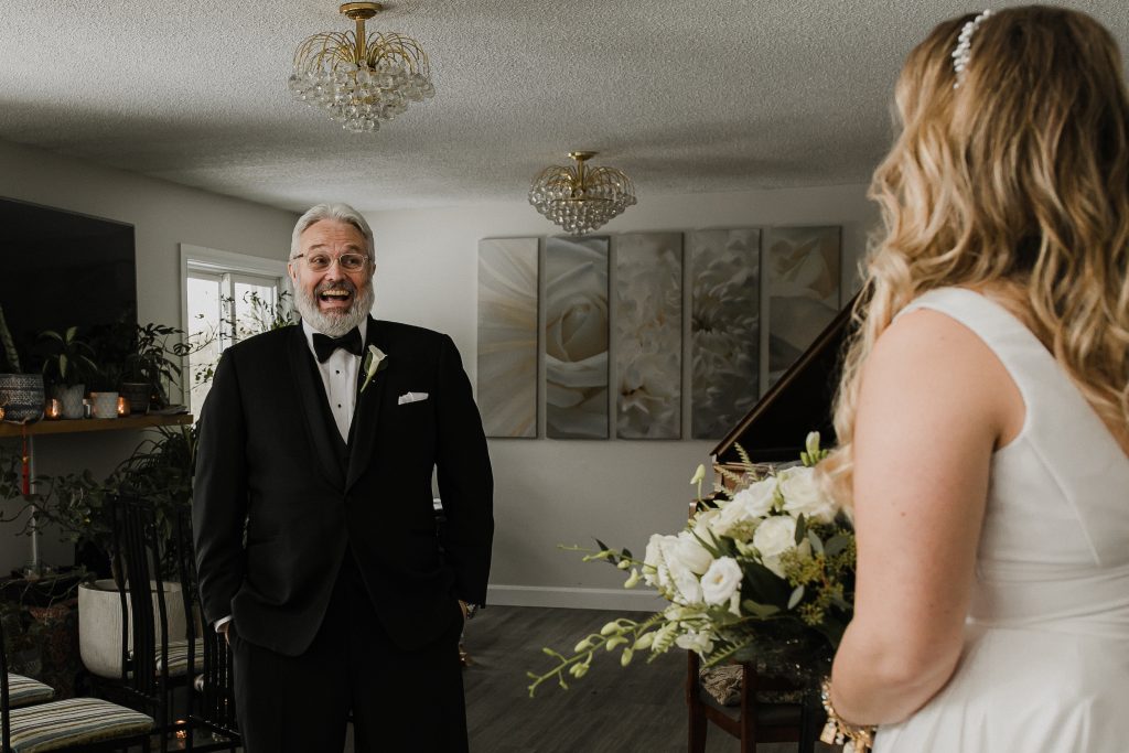 Father smiling at bride at intimate home wedding. Photographed by Peterborough Wedding Photographer.