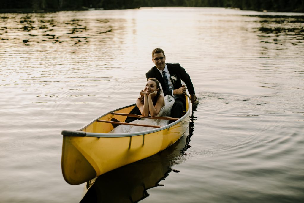 Groom paddling bride in canoe at sunset in Kawartha Lakes