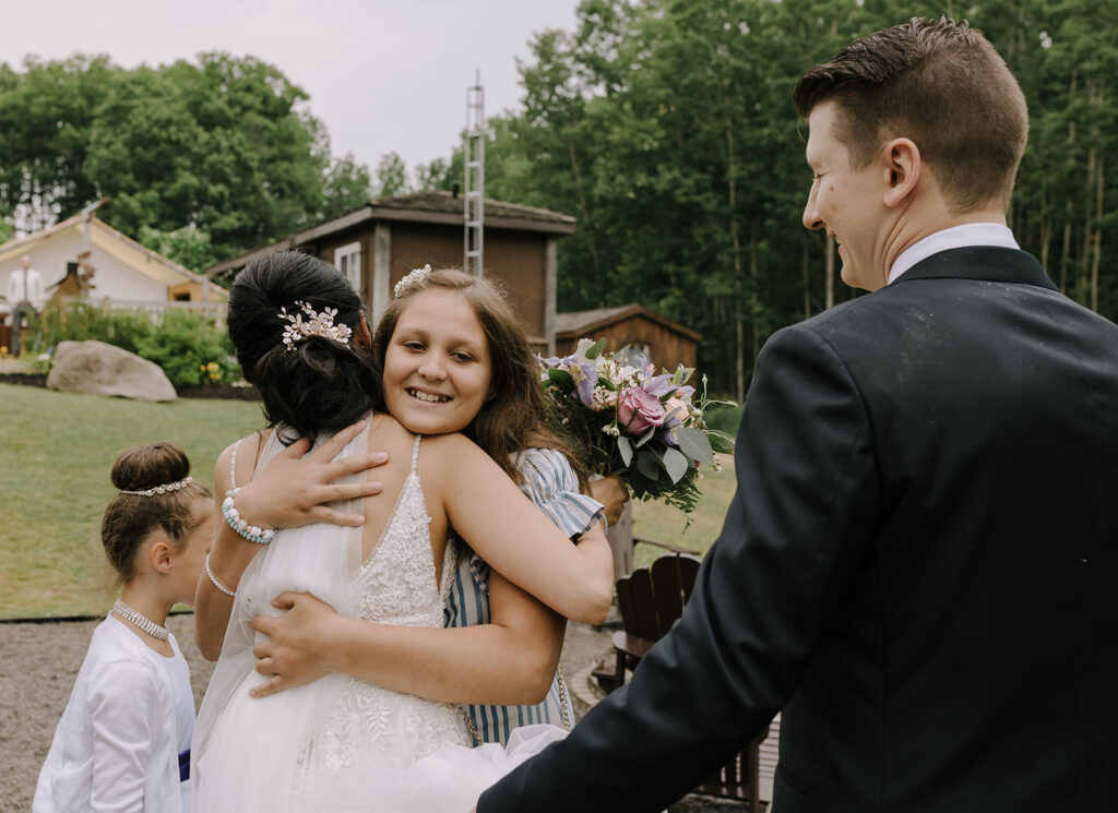 Candid moment of bride hugging wedding guests after Ontario wedding ceremony.