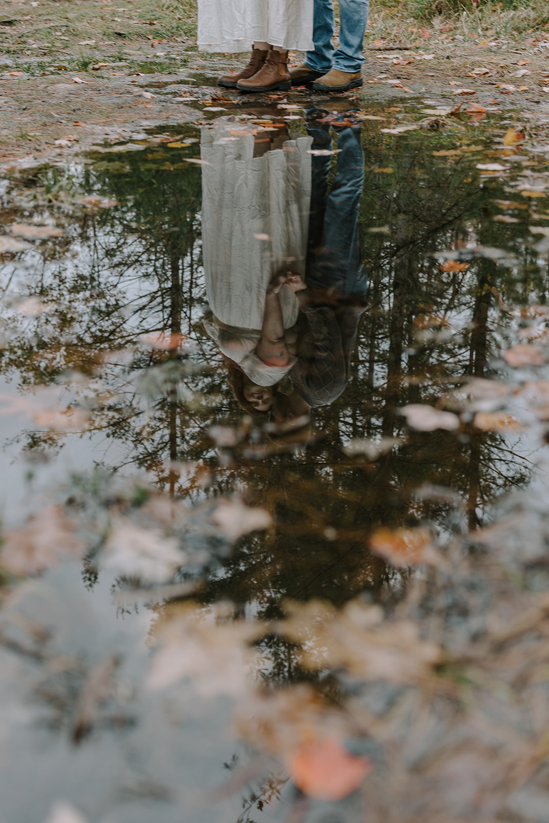 Couple reflected in forest puddle during romantic fall engagement session at Kawartha Highlands Provincial Park near Buckhorn Ontario